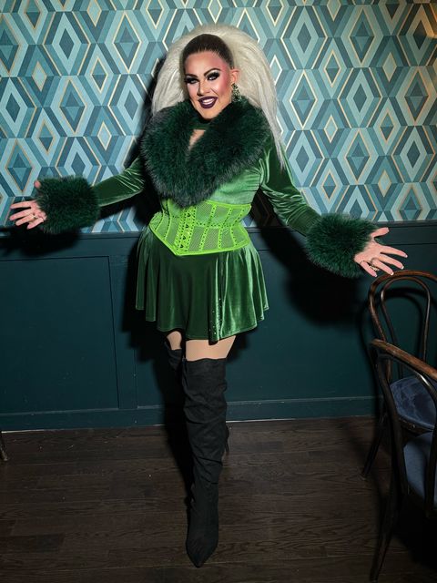 Abby Cummings in green velvet, arms open, in a Boston bar